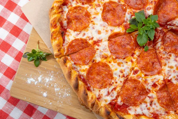 Піца Пепероні крупним планом з різними інгредієнтами, прикрашеними базиліком Стокове Зображення