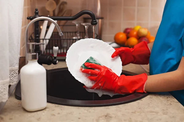 Washing the dishes after a meal - child hands scrubbing a plate — Stock Photo, Image