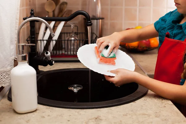 Criança lavando um prato com esponja na pia da cozinha, rasa d — Fotografia de Stock