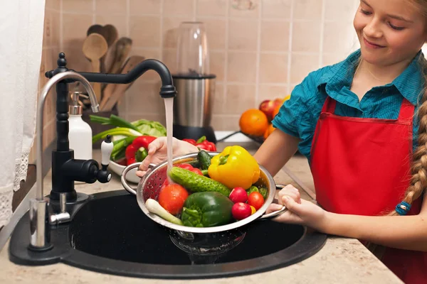 Ung flicka tvätta grönsaker i en sil, grunt djup — Stockfoto