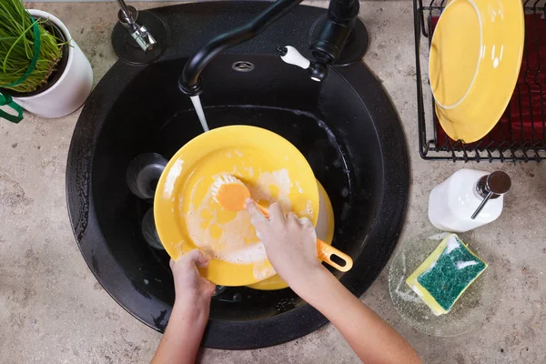 Детские руки моют тарелку в раковине на кухне — стоковое фото