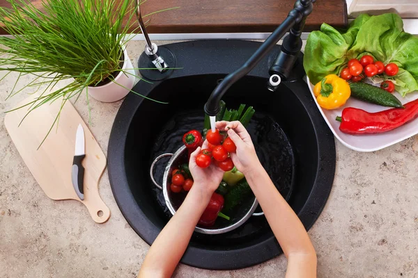 Barn händer tvätt grönsaker på diskbänken — Stockfoto