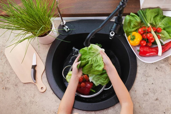 Las manos infantiles lavando hortalizas en el fregadero de la cocina - la lechuga — Foto de Stock