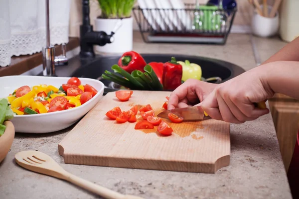 Mani di bambino affettare pomodoro ciliegia per un'insalata di verdure fresche — Foto Stock