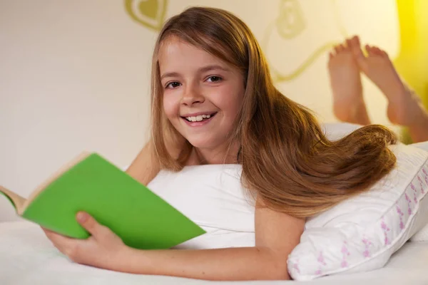 Jong meisje het lezen van een boek in bed — Stockfoto