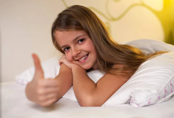 Jong meisje met duimen omhoog ondertekenen met een grijns, ondiepe diepte — Stockfoto
