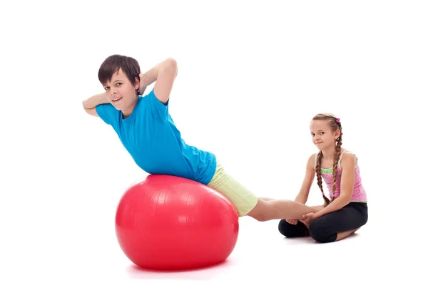 Niños ayudándose unos a otros haciendo ejercicio con una gran goma gimnástica —  Fotos de Stock