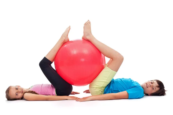 Niño y niña haciendo ejercicio con una gran pelota de goma gimnástica — Foto de Stock