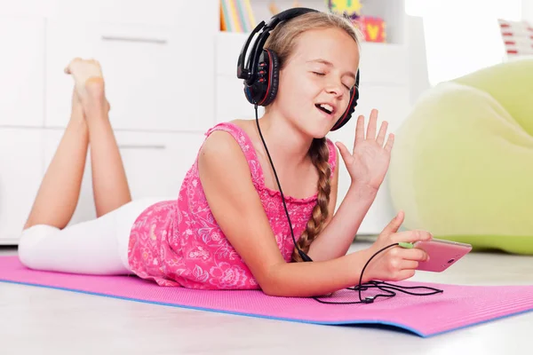 Young girl singing a tune listening to music on her phone — Stock Photo, Image