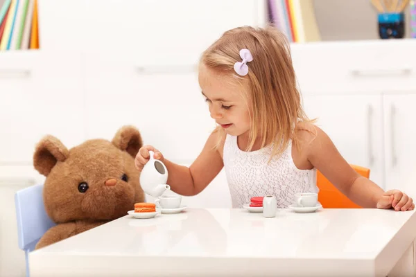 Маленькая девочка подает чай своему игрушечному медведю — стоковое фото