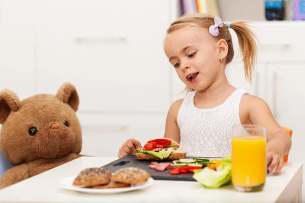 Malá holčička s zdravou svačinku sedí u stolu s ní — Stock fotografie