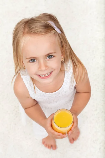 Niña feliz tomando un vaso de jugo de frutas - vista superior — Foto de Stock