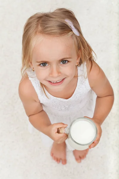 Liten glad tjej som håller en kopp mjölk - ovanifrån — Stockfoto