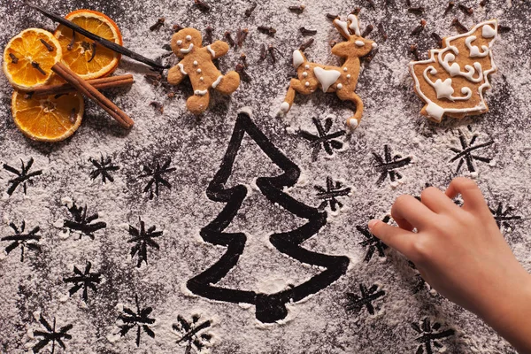 Child hand drawing holidays scene in the flour prepared for the