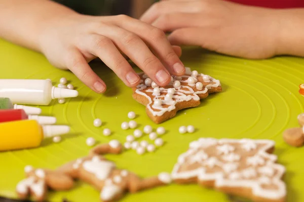 As mãos de criança decoram biscoitos de Natal - close-up — Fotografia de Stock