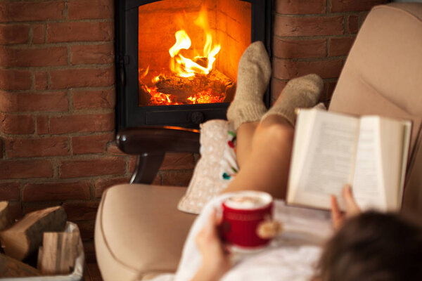 Woman enjoying free time by the fire - reading a book