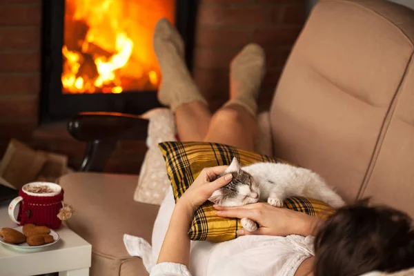 Woman enjoying the fire and some fine company - her kitten — Stock Photo, Image