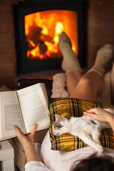 Женщина читает у костра - расслабляется со своей кошкой — стоковое фото