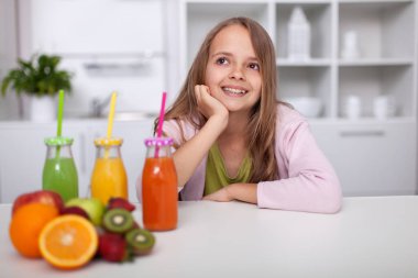 Genç kız mutfakta elinde taze şişelerle oturuyor.