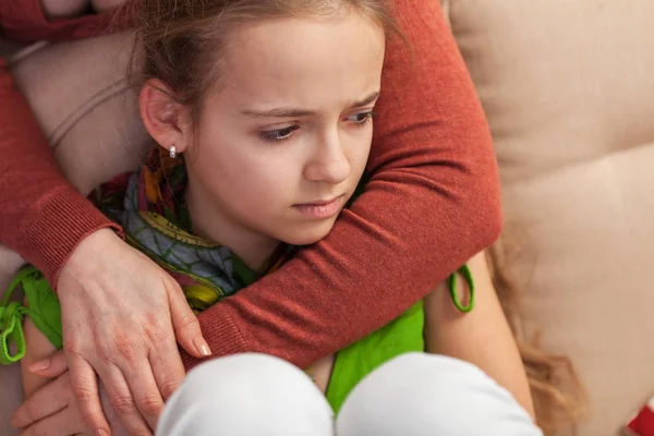 Besorgtes und trauriges junges Mädchen auf Sofa sitzend - Frau umarmt und lizenzfreie Stockfotos
