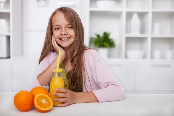 Молодая девушка-подросток с широкой улыбкой и свежевыжатым апельсином — стоковое фото