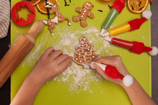 子供の手はクリスマスジンジャーブレッドクッキーを飾る-トップビュー — ストック写真