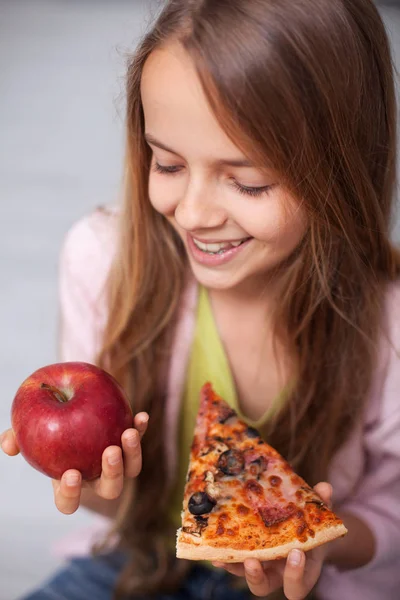 Lanche de fast food ou lanche de frutas - menina sorridente ponderando comer — Fotografia de Stock