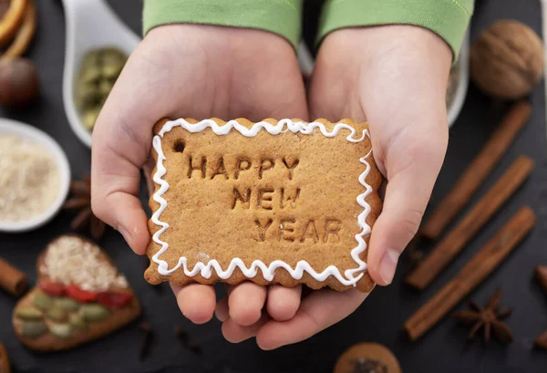 Young girl hands hold gingerbread biscuit with happy new year te — Stock Photo, Image