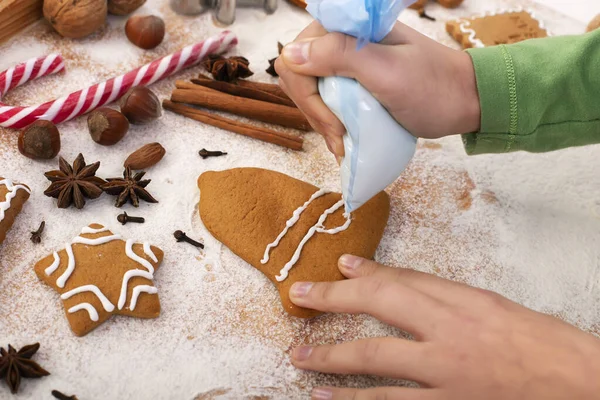 Young hands decorate gingerbread cookies with white icing applie — Stock Photo, Image