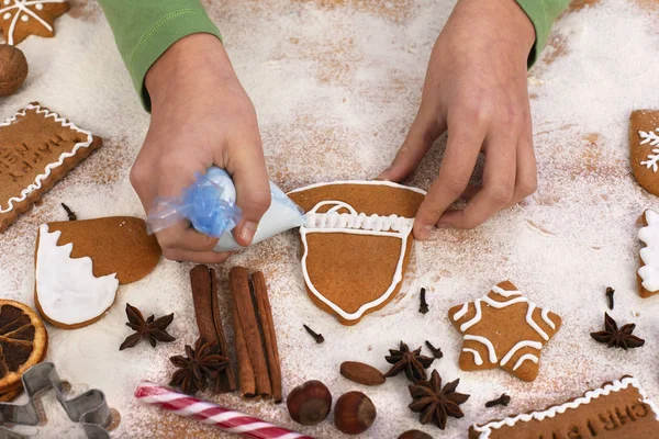 Las manos de niña decoran galletas de jengibre con glaseado blanco  - — Foto de Stock