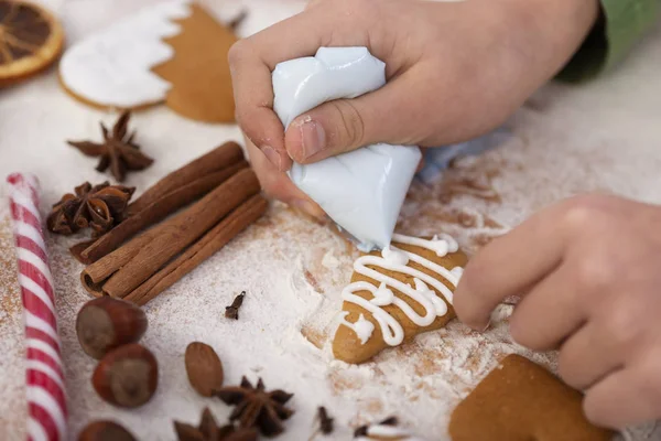 Mladé ruce zdobí perník sušenky s bílou polevou — Stock fotografie