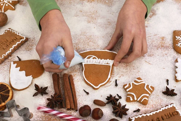 Junge Mädchenhände dekorieren Lebkuchen mit weißem Zuckerguss - Stockfoto