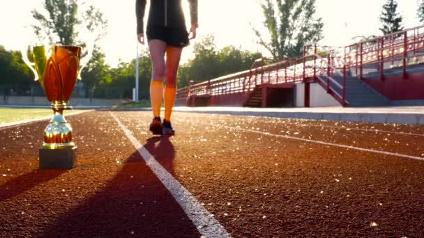 Laufwettbewerb Anfänger. schöne Mädchenbeine mit goldenem Siegerpokal — Stockvideo