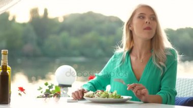 Çekici sarışın kız bir salata restoranda yiyor.