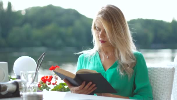 Красива дівчина читає книгу в кафе . — стокове відео