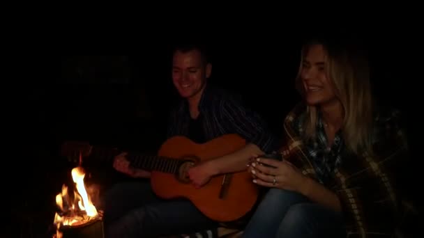 Feliz jovem casal tocando música e desfrutar de fogueira ao ar livre — Vídeo de Stock