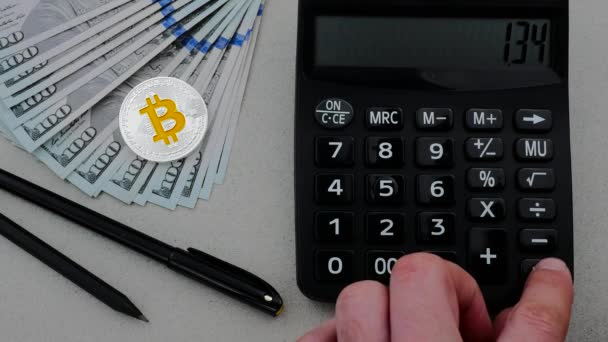 Silver bitcoin with many dollars on the working table and calculator — Stock Video