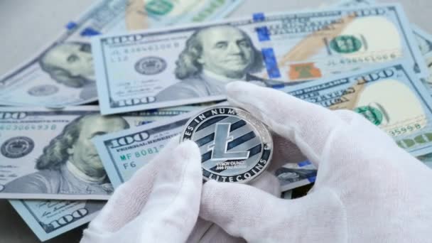 Händer i vita handskar undersöka Litecoin kryptovaluta på Usd dollar bakgrunden — Stockvideo