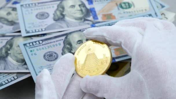 Hands in white gloves examine gold cryptocurrency on the USD dollars background — Stock Video