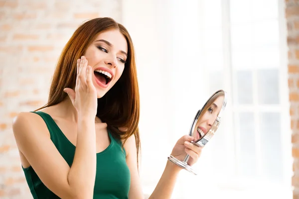 Молодая женщина с зеркалом, в помещении — стоковое фото