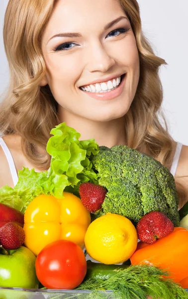 Mujer joven con comida vegetariana, sobre gris —  Fotos de Stock
