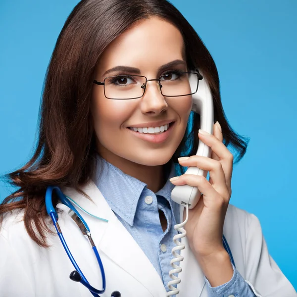 Sonriente joven médico con teléfono, en azul —  Fotos de Stock