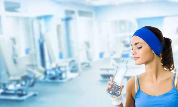 Mujer en ropa deportiva agua potable, en el gimnasio —  Fotos de Stock