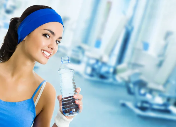 Mujer en ropa deportiva agua potable, en el gimnasio — Foto de Stock