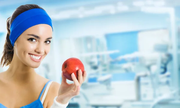 Γυναίκα σε αθλητικά ενδύματα με μήλο, στο γυμναστήριο — Φωτογραφία Αρχείου