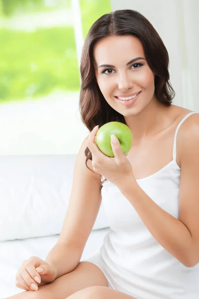 Giovane donna felice sorridente con mela verde, in casa — Foto Stock