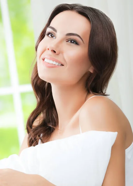 Mladá krásná usměvavá žena probuzení s polštářem, v ložnici — Stock fotografie