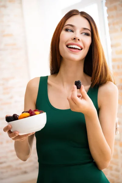 Mulher sorridente com prato de frutas, dentro de casa — Fotografia de Stock