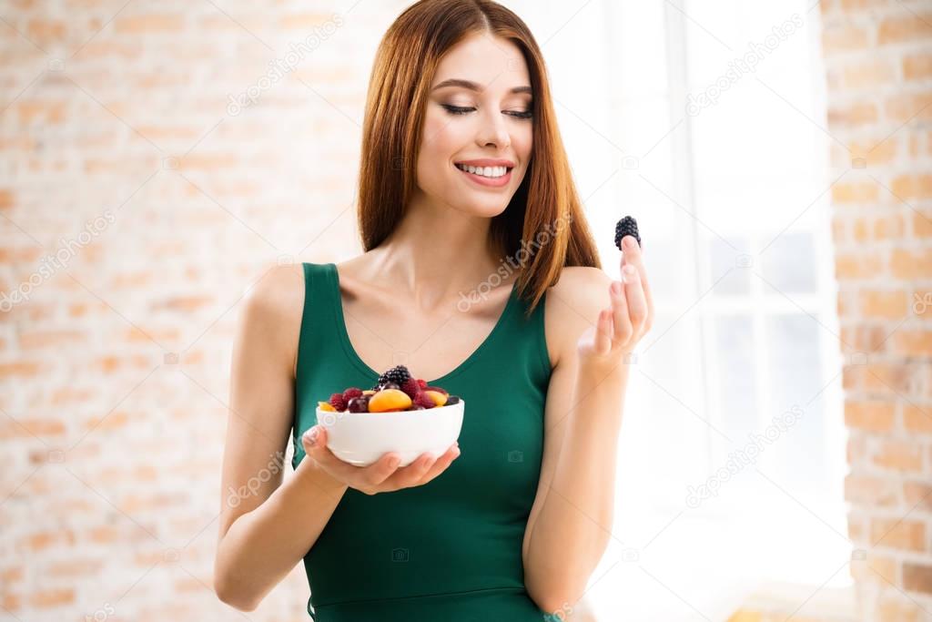 Smiling woman with plate of fruits, indoors