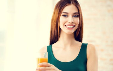 mutlu gülümseyen genç kadın portakal suyu içme
